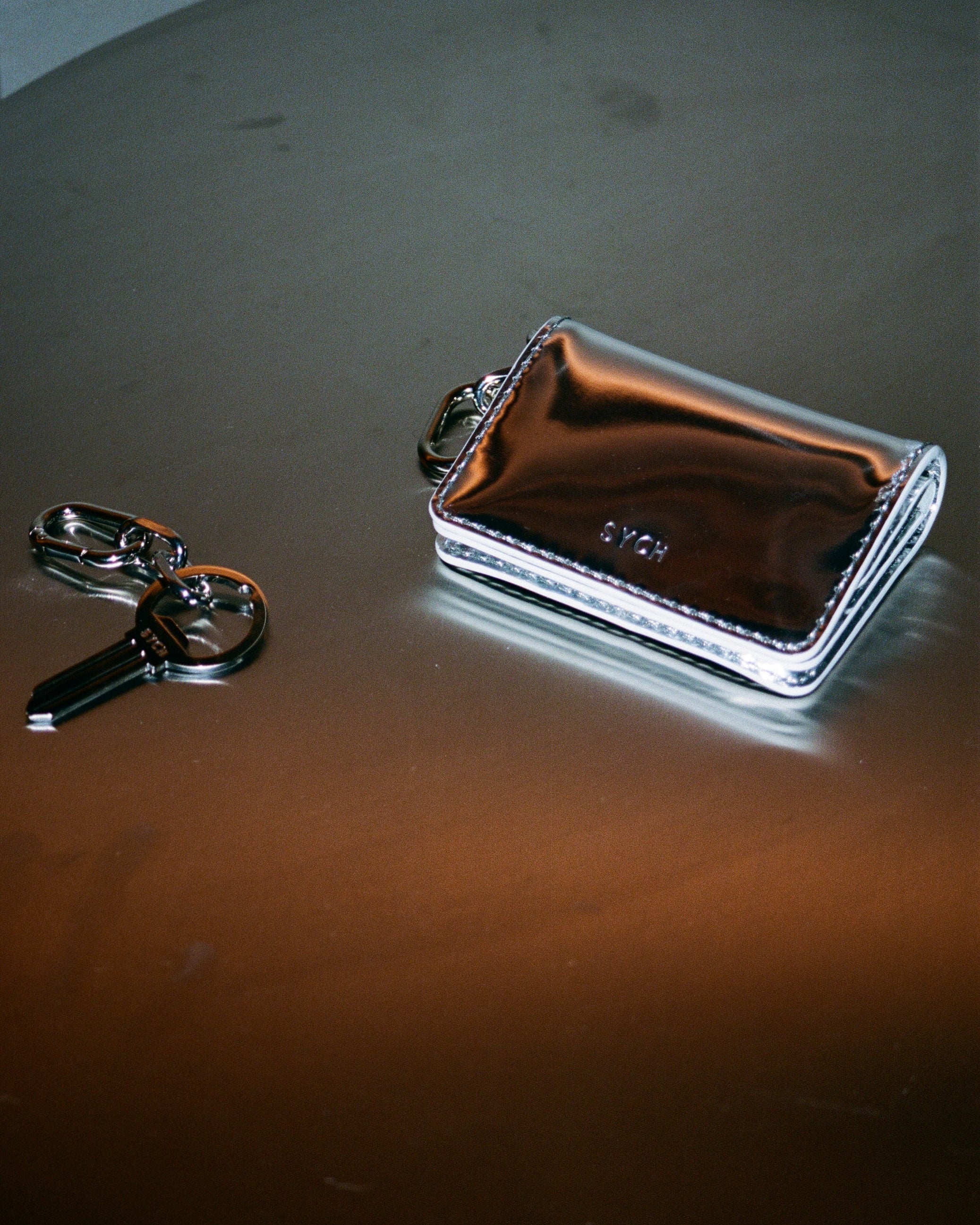 Sych silver bottle opener keyring in the shape of a key with a chain and silver tobacco pouch
